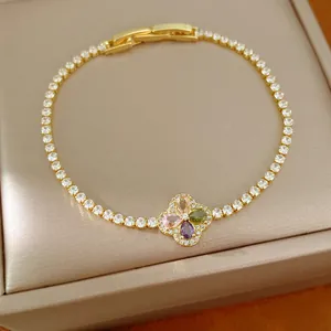 Detail van een gouden klaverarmband met gekleurde zirkoonstenen op een displaydoos