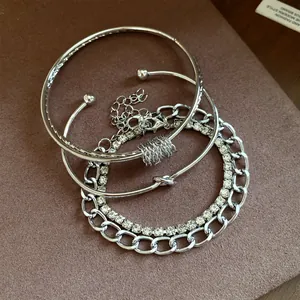 Primo piano di un set di quattro bracciali argentati con strass e catene
