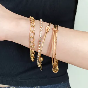 Dettaglio di un set di 4 braccialetti dorati con strass e design a nodo sul braccio