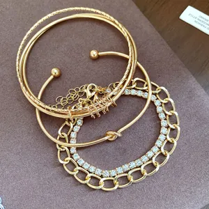 Primo piano di un set di 4 braccialetti d'oro con strass, catene e nodi