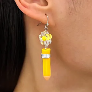 Detail view of creative yellow pencil drop earring with a flower bead decoration