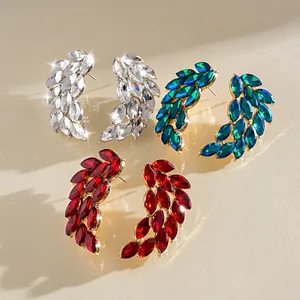 Detailed close-up view of elegant wing-shaped rhinestone stud earrings in silver, green, and red