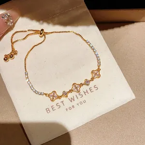 Detaillierte Makroaufnahme eines Goldkleearmbandes mit rosa Zirkonia auf einem Geschenkbeutel