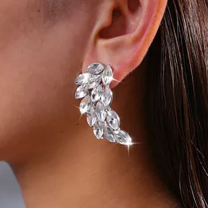 Detailed close-up view of elegant sparkling rhinestone feather earrings on model's ear