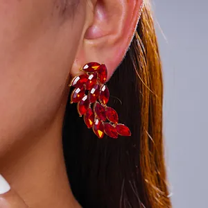 Detailed macro view of a luxury red rhinestone feather wing stud earring on model