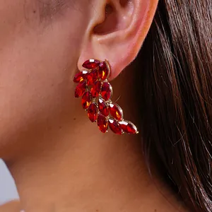 Detailed macro shot of elegant red feather wing rhinestone stud earrings on a model ear