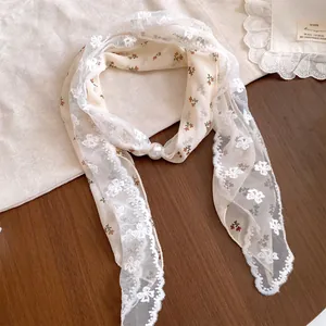 Detailopname van een zoete dubbellaagse sjaalketting van kant en bloemenprint met parel