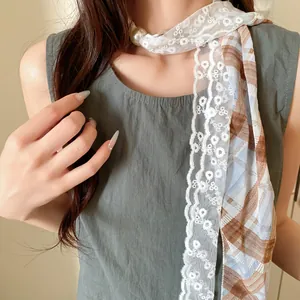 Detail van een zoete kanten en ruitjes sjaalketting met een prachtig groot parelaccent.