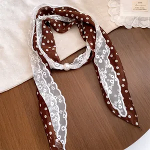 Detail van bruine polkadot sjaalketting met wit kant en een parel