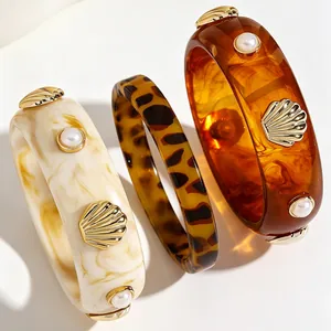 Close-up of vintage resin bangles with pearl and shell accents in tortoise amber tones