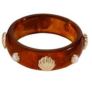 Detailed view of vintage amber resin bangle featuring gold scallop shells and pearls.