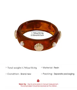 Detailed view of wide amber resin bangle with shell and pearl accents and size specs
