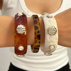 Close-up of vintage resin wide bangles featuring metallic shell and pearl embellishments
