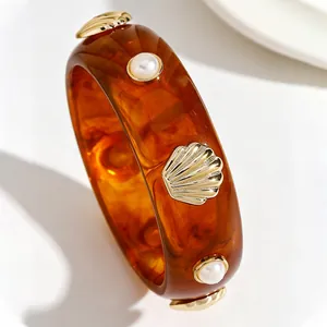 Detail of retro resin bangle with tortoiseshell pattern and shell pearl accents.