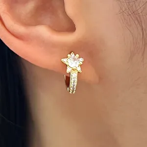 Close-up of elegant gold star-shaped earrings with micro-pave crystals on model's ear