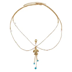Detailed view of a multilayer gold body chain featuring a turtle pendant and blue beads