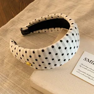 Gros plan détaillé du serre-tête rétro blanc à pois noirs avec petit bouton doré élégant