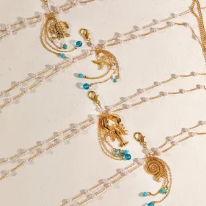 Detail view of gold multi-layered body chains with sea-themed lobster and shell charms.
