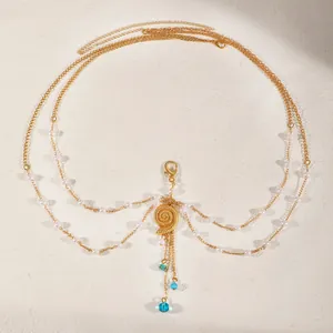 Macro detail of gold multilayer body chain featuring a seashell pendant and elegant faux pearls