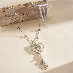 Primer plano de collar de llave de corazón de plata con perla y cinta blanca