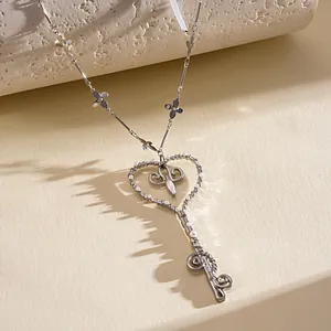 Primer plano de collar de llave en forma de corazón con perlas y eslabones de flores