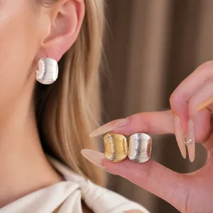 Boucles d'oreilles clous minimalistes en métal texturé en forme de C sur modèle et main