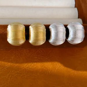 Gros plan détaillé de boucles d'oreilles en métal en forme de C texturées or et argent