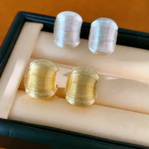 Détail macro de boucles d'oreilles en C dorées et argentées avec une texture linéaire