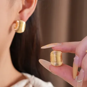 Gros plan détaillé sur des boucles d'oreilles dorées en forme de C avec texture