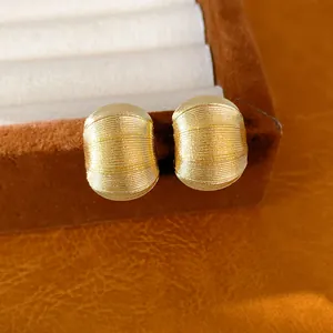 Gros plan détaillé de boucles d'oreilles dorées texturées en forme de C sur velours