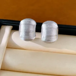Gros plan de boucles d'oreilles clous en forme de C argentées à texture fine