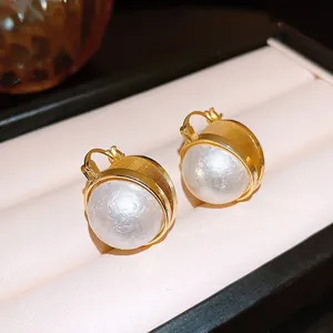 Vintage vergulde oorbellen met grote witte parels gepresenteerd in een sieradendoosje.