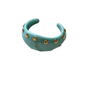 Bracelet jonc vintage en acrylique bleu clair avec clous dorés sur fond blanc
