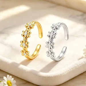 Detailaufnahme goldener und silberner offener Ringe mit funkelnden Gänseblümchen