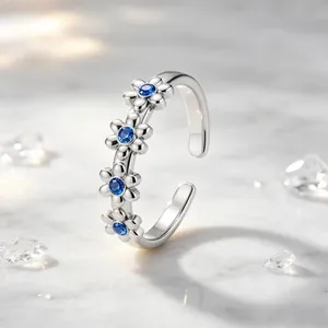 Eleganter offener Gänseblümchenring mit vier blauen Zirkonia auf Marmorhintergrund