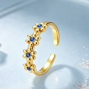 Detaillierte Nahaufnahme von einem goldenen Gänseblümchen-Ring mit blauen Steinen