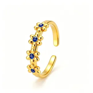 Detailaufnahme eines offenen Edelstahlrings in Gold mit blauen Kristall-Gänseblümchen