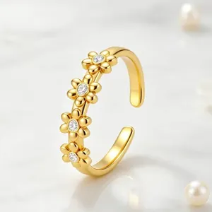 Detailansicht eines goldenen Edelstahlrings mit vier eleganten Gänseblümchen aus Kristall