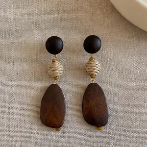 Close-up of vintage boho wooden drop earrings with woven straw beads on linen background