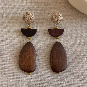 Close-up of bohemian geometric drop earrings with woven balls and wooden pendants