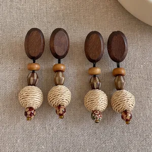 Detailed view of bohemian wood and woven straw drop earrings on linen background