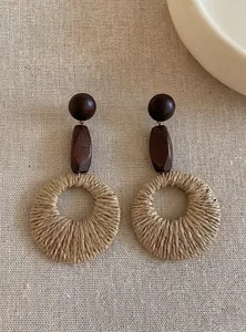Detailed view of bohemian wood and woven straw round drop earrings on linen background