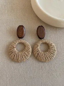 Macro view showing natural wood texture and straw weaving on bohemian hoop earrings