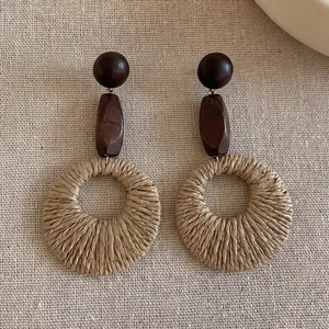 Detailed close-up of bohemian earrings with wooden beads and woven raffia rings