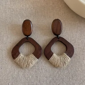 Close-up detail of geometric wooden earrings with handmade rustic woven rope accents