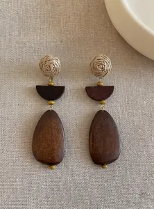 Detailed view of handmade wooden geometric drop earrings with woven straw and wood textures