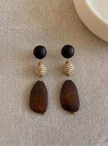 Close-up detail of vintage geometric wood earrings featuring woven beads on linen texture