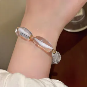 Vista detallada de una pulsera de resina transparente con elegantes motivos blancos