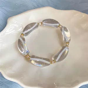 Primer plano detallado de una pulsera de resina con rayas blancas y toques dorados
