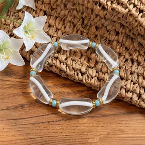 Vista detallada de una pulsera de resina transparente y cuentas azules sobre fondo de paja